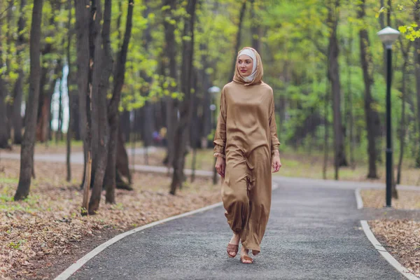 Mulher bonita islâmica em um vestido muçulmano de pé em um parque de verão rua fundo floresta outono trees.world hijab dia. — Fotografia de Stock