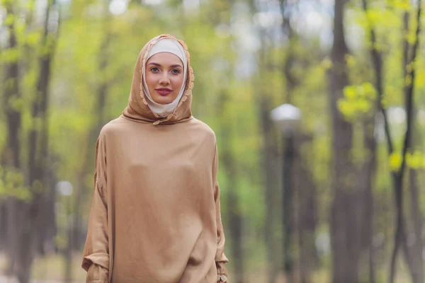 Wanita cantik Islam dalam gaun Muslim berdiri di taman musim panas latar belakang hutan musim gugur pohon. Hari hijab dunia. — Stok Foto