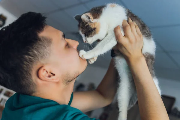 Mladý muž v tričku drží kočku. — Stock fotografie