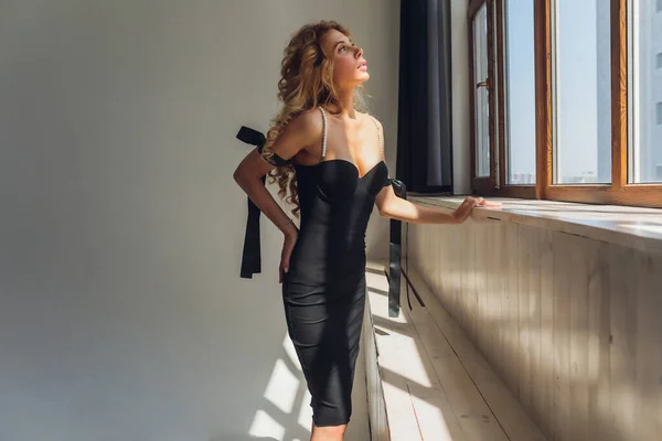 Блондинка средних лет в черном платье позирует на сером фоне. — стоковое фото