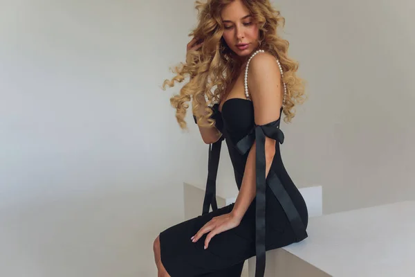 Блондинка средних лет в черном платье позирует на сером фоне. — стоковое фото
