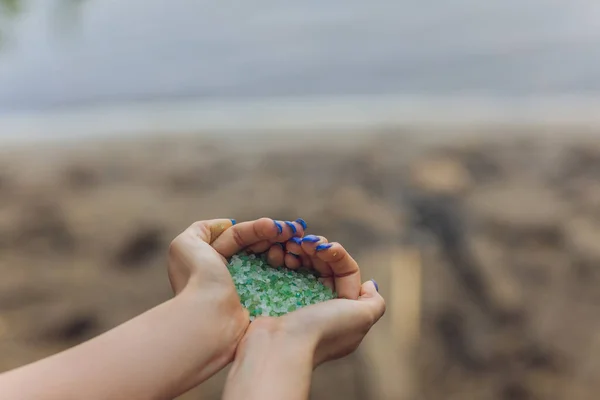 Pequenos pedaços de plástico recolhidos de praia arenosa em mãos de ambientalista. Microplástico está poluindo o mar e ecossistema marinho. — Fotografia de Stock
