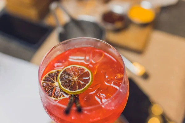 Делаю коктейль "Восход Текилы". Гренадин медленно вливается в стакан льда, апельсинового сока и текилы. — стоковое фото