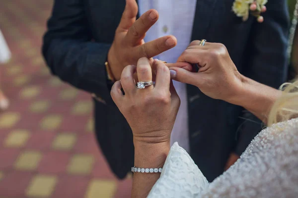 Noiva que põe uma aliança de casamento no dedo de noivos. — Fotografia de Stock