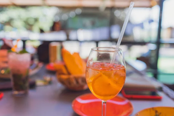 Making Tequila Sunrise Cocktail. Grenadine slowly poured into a glass of ice, orange juice and tequila.