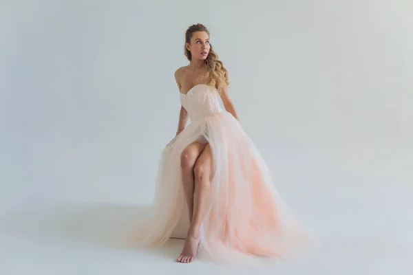 Mujer rubia de mediana edad en vestido rosa posando sobre fondo gris. — Foto de Stock