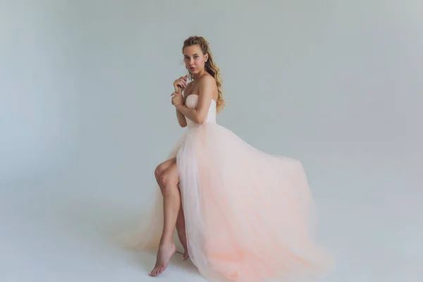 Mujer rubia de mediana edad en vestido rosa posando sobre fondo gris. — Foto de Stock