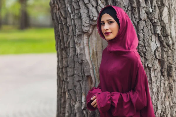 Selbstbewusster arabischer Geschäftsmann lächelt und spaziert durch Dubai. Arab Business vumen hijab ist auf den Straßen gegen die Wolkenkratzer von Dubai. Die Frau ist mit einer schwarzen Abaya bekleidet. — Stockfoto
