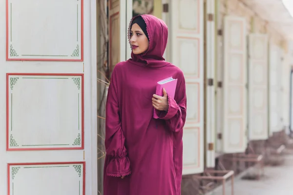Hombre de negocios árabe confiado sonriendo y paseando por Dubai. Arab Business vumen hijab está en las calles contra los rascacielos de Dubai. La mujer está vestida con una abaya negra.. — Foto de Stock