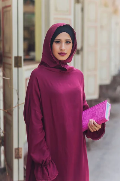 Hombre de negocios árabe confiado sonriendo y paseando por Dubai. Arab Business vumen hijab está en las calles contra los rascacielos de Dubai. La mujer está vestida con una abaya negra.. — Foto de Stock