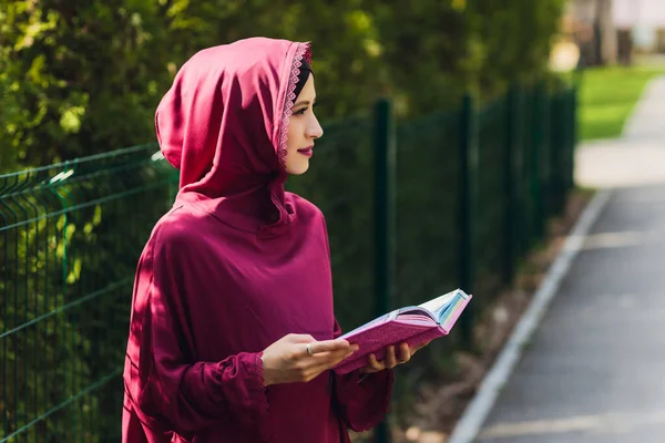 Selbstbewusster arabischer Geschäftsmann lächelt und spaziert durch Dubai. Arab Business vumen hijab ist auf den Straßen gegen die Wolkenkratzer von Dubai. Die Frau ist mit einer schwarzen Abaya bekleidet. — Stockfoto