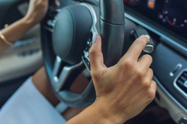 Kadınların elleri direksiyondaki dişli seçicinin loblarını değiştiriyor. El, araba vites kolunu değiştiriyor. El teçhizatı yakın çekim. Direksiyon simidinin küreğini değiştiriyor..