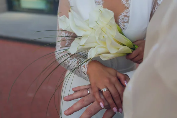 Bruid en bruidegom hand in hand. Trouwringen en bruidsboeket detail. — Stockfoto