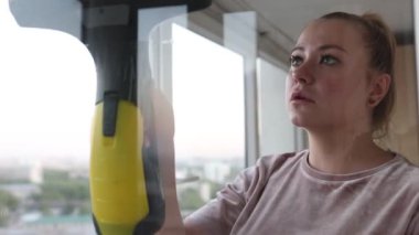 İş kıyafetleri içinde, evdeki profesyonel aletlerle pencereleri yıkayan güzel bir ev hanımı..