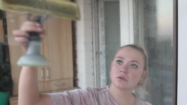 Vacker ung hemmafru i arbetskläder tvätta fönster med professionella verktyg hemma. — Stockvideo