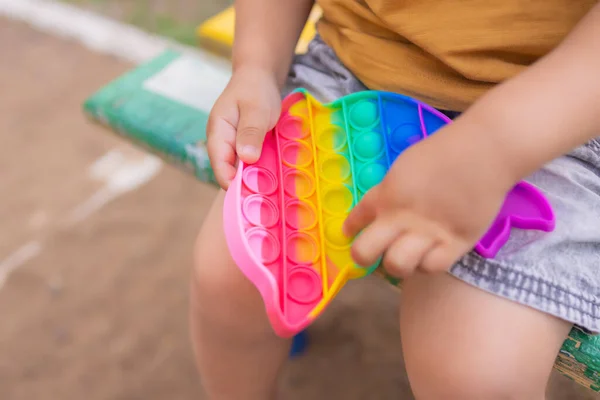 Colorful antistress sensory toy fidget push pop it in toddlers hands. Antistress trendy pop it toy. Rainbow sensory fidget. New trendy silicone toy. dolphin shape — Fotografia de Stock