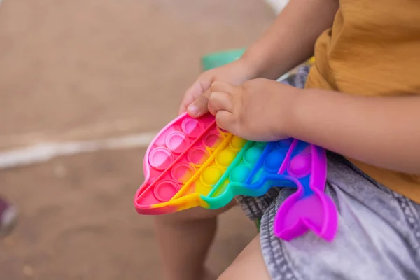 Colorful antistress sensory toy fidget push pop it in toddlers hands. Antistress trendy pop it toy. Rainbow sensory fidget. New trendy silicone toy. dolphin shape — Stok fotoğraf