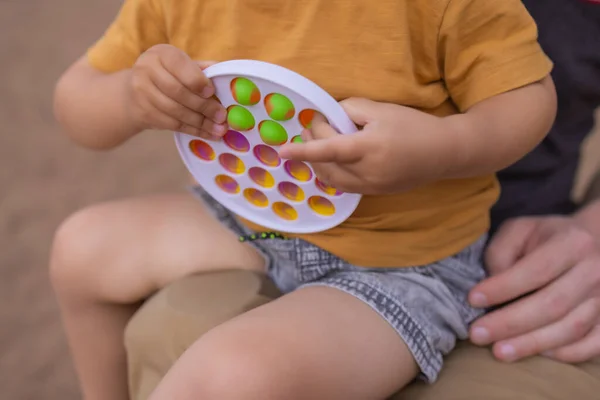 Bunte antistress-sensorische Spielzeug-Fidget-Push-Push in Kleinkindhänden. Antistress trendy pop it toy. Regenbogensensorik zappelt. Neues trendiges Silikonspielzeug. — Stockfoto