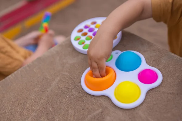 Colorful trendy antistress sensory toy fidget push pop it and simple dimple in kids hands, children share toys and playing together. — Fotografia de Stock