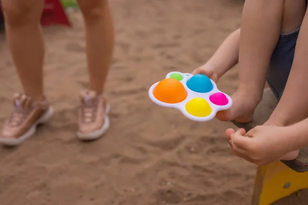 Colorful trendy antistress sensory toy fidget push pop it and simple dimple in kids hands, children share toys and playing together. — Stockfoto