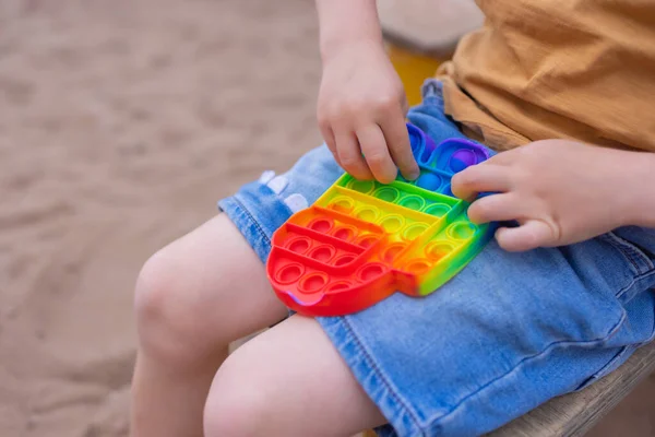 Färgglada antistress sensoriska leksak fidget skjuta pop den i småbarn händer. Antistress trendiga pop den leksak. Regnbågssensorisk fiol. Ny trendig silikonleksak. — Stockfoto