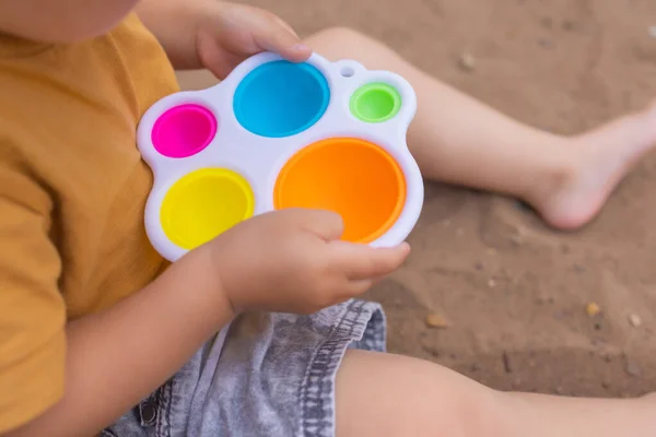 Colorful trendy antistress sensory toy fidget push pop it and simple dimple in kids hands, children share toys and playing together. — Fotografia de Stock