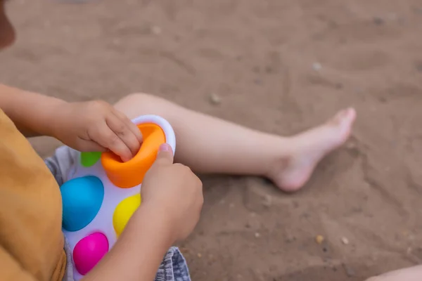 Colorful trendy antistress sensory toy fidget push pop it and simple dimple in kids hands, children share toys and playing together. — Fotografia de Stock