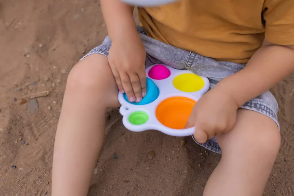 Colorful trendy antistress sensory toy fidget push pop it and simple dimple in kids hands, children share toys and playing together. — Fotografia de Stock