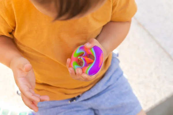 Colorido antistress brinquedo sensorial violeta empurrá-lo pop-lo em mãos de crianças. Antistress moda pop-lo brinquedo. Arco-íris fidget sensorial. Novo brinquedo de silicone na moda. Parafusos — Fotografia de Stock
