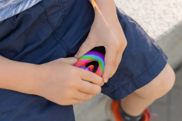 Colorido antistress brinquedo sensorial violeta empurrá-lo pop-lo em mãos de crianças. Antistress moda pop-lo brinquedo. Arco-íris fidget sensorial. Novo brinquedo de silicone na moda. Parafusos — Fotografia de Stock