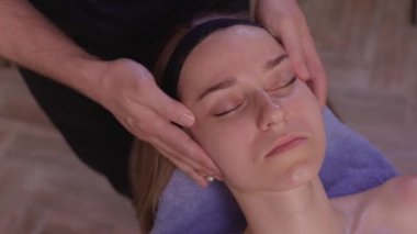 Kadın yüzüne masaj yapan masözlerin ellerini kapatın. Kadın zevkle gözlerini kapadı..