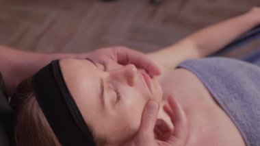 Kadın yüzüne masaj yapan masözlerin ellerini kapatın. Kadın zevkle gözlerini kapadı..