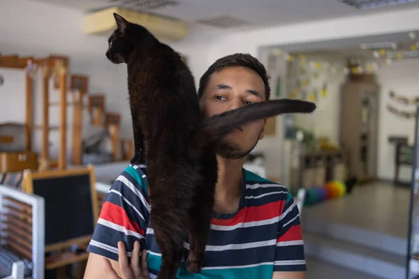 Young man in t shirt holding a cat. — Stock Photo, Image