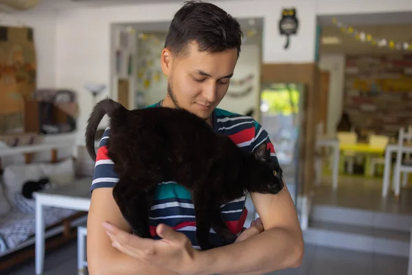 Tシャツを着た若い男が猫を抱いて. — ストック写真
