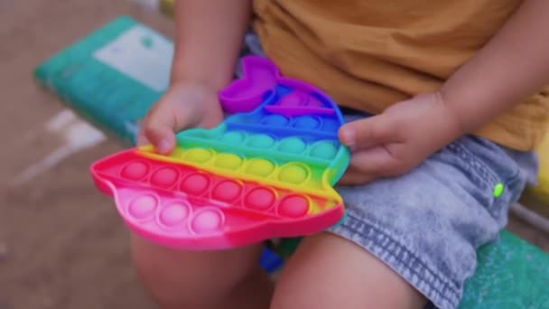 Färgglada antistress sensoriska leksak fidget skjuta pop den i småbarn händer. Antistress trendiga pop den leksak. Regnbågssensorisk fiol. Ny trendig silikonleksak. — Stockvideo