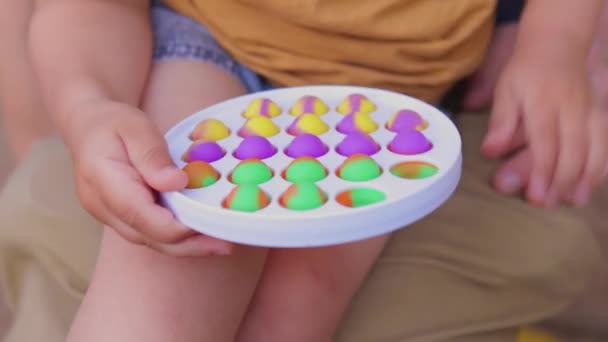 Bunte antistress-sensorische Spielzeug-Fidget-Push-Push in Kleinkindhänden. Antistress trendy pop it toy. Regenbogensensorik zappelt. Neues trendiges Silikonspielzeug. — Stockvideo