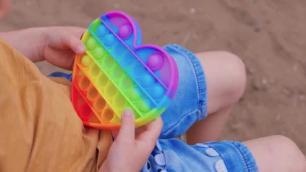 Barevné antistresové smyslové hračka vrtění tlačit pop to v batolata ruce. Antistress trendy pop it toy. Duhový smyslový vrtění. Nová trendy silikonová hračka. — Stock video