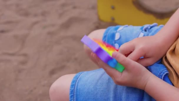 Bunte antistress-sensorische Spielzeug-Fidget-Push-Push in Kleinkindhänden. Antistress trendy pop it toy. Regenbogensensorik zappelt. Neues trendiges Silikonspielzeug. — Stockvideo