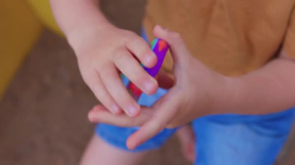 カラフルな抗ストレス感覚おもちゃのフィジェットは幼児の手でそれをプッシュします。アンチストレストレンディーなポップそれおもちゃ。虹の感覚のフィジェット。新しいトレンディーなシリコーンおもちゃ。狙撃手 — ストック動画