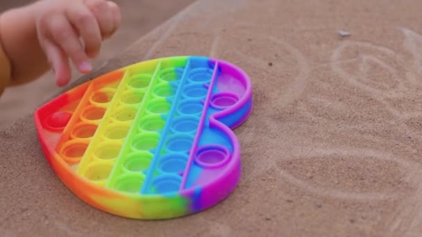 Bunte antistress-sensorische Spielzeug-Fidget-Push-Push in Kleinkindhänden. Antistress trendy pop it toy. Regenbogensensorik zappelt. Neues trendiges Silikonspielzeug. — Stockvideo