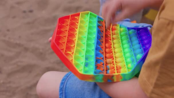 Bunte antistress-sensorische Spielzeug-Fidget-Push-Push in Kleinkindhänden. Antistress trendy pop it toy. Regenbogensensorik zappelt. Neues trendiges Silikonspielzeug. — Stockvideo