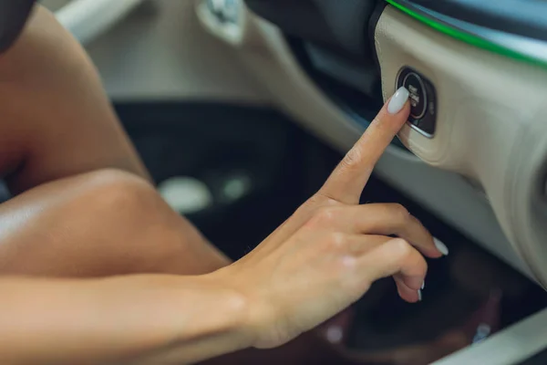 Vrouwelijke hand met startsleutel binnen auto. — Stockfoto