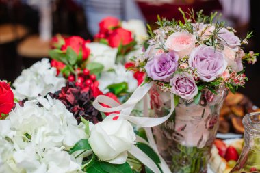 Tuğla duvara karşı farklı taze çiçeklerden oluşan renkli bir buket. Bir demet orkide, güller, frezya ve okaliptüs yaprakları. Kırsal çiçek arka planı. Üst görünüm.