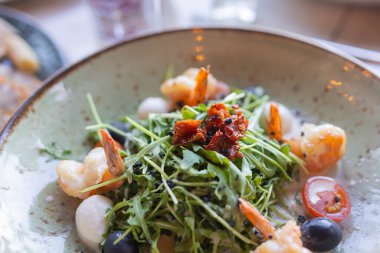 Lezzetli karides, roka, ıspanak, lahana, roka, yumurta, parmesan ve vişneli domates salatası. Yağ, tuz ve biber. Sağlıklı ve diyet gıda konsepti.