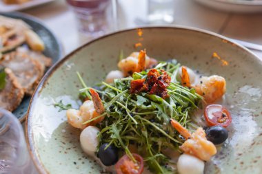 Lezzetli karides, roka, ıspanak, lahana, roka, yumurta, parmesan ve vişneli domates salatası. Yağ, tuz ve biber. Sağlıklı ve diyet gıda konsepti.