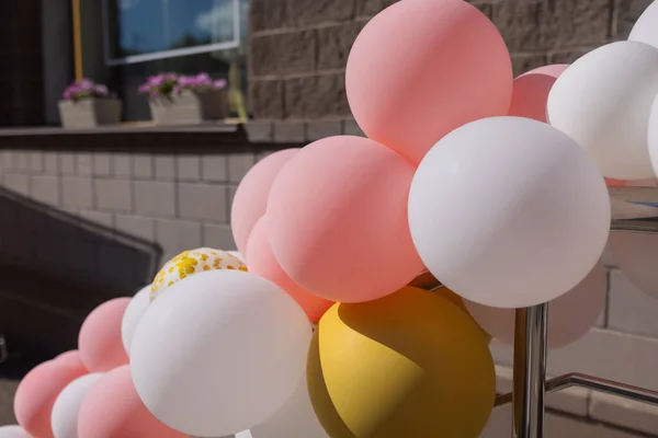 Globos están unidos a la barandilla del porche. Apertura de la tienda. Pared de crema, escalera roja. Luz del sol brillante y sombras. Fondo de calle festivo. — Foto de Stock