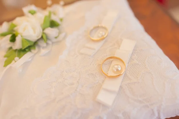 Close-up van gouden trouwringen op decoratief wit kanten kussen. — Stockfoto