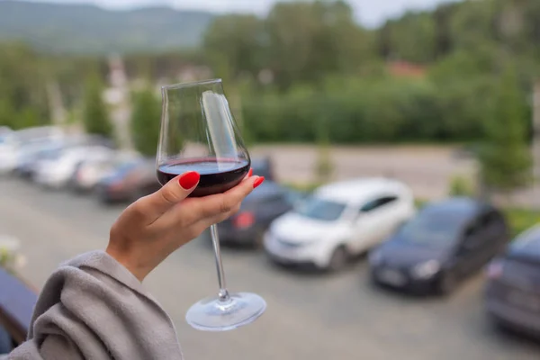 Männliche Hand hält Glas mit Wein auf verschwommenem natürlichen Hintergrund. — Stockfoto
