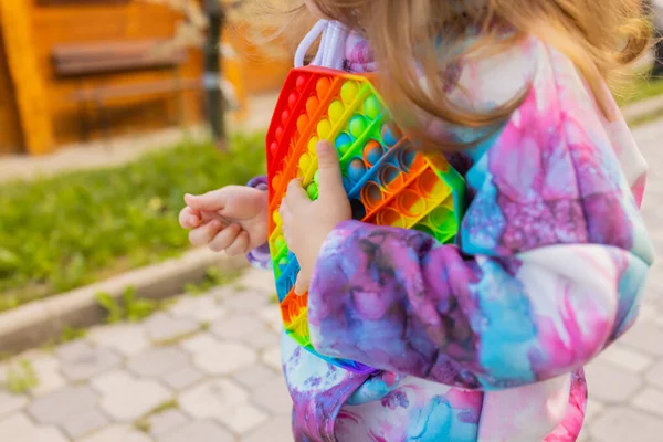 Pop-lo brinquedo fidget em mãos de menina. colorido antistress crianças brinquedo fidget. — Fotografia de Stock