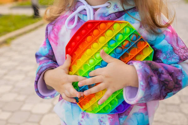 Pop it fidget jouet dans les mains des filles. Jouet anti-stress coloré pour enfants violon. — Photo